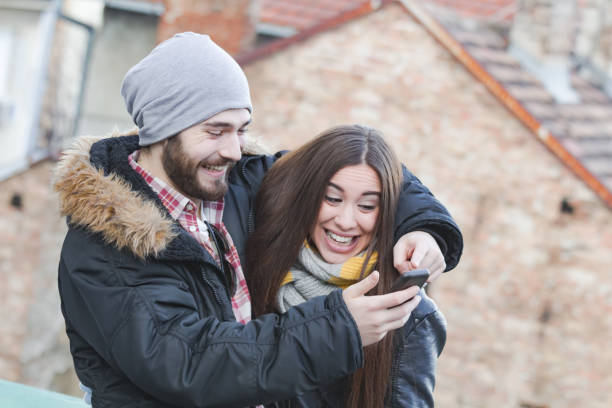 istock Couple using cellphone in cold winter times outdoors. 1200893038
