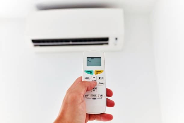 istock Modern air conditioner unit with a hand holding a remote. 1200894274