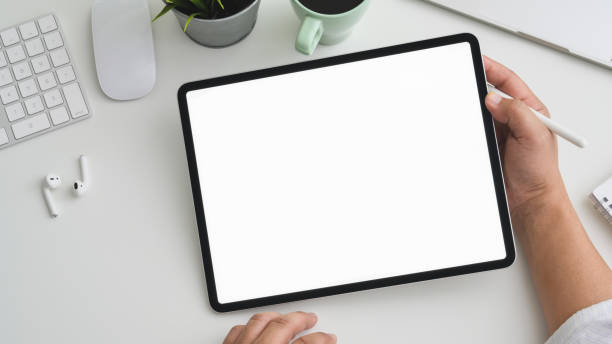 istock Overhead shot of Businessman working on tablet in modern workspace with computer, laptop and office supplies 1200894510