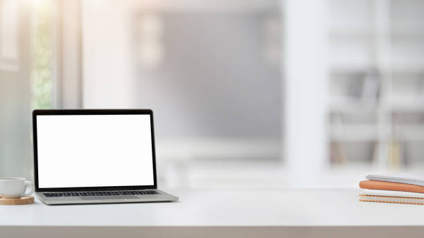 istock Close up view of workplace with blank screen laptop, copy space, notebooks and coffee cup on white table 1200894650