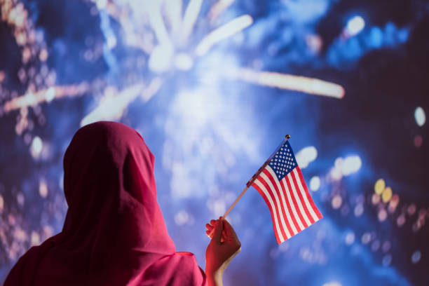 muslimische frau in einem schal hält amerikanische flagge während feuerwerk in der nacht. - people traveling flash stock-fotos und bilder