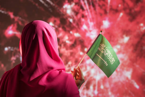 mulher muçulmana em um cachecol segurando bandeira da arábia saudita durante fogos de artifício à noite. - eastern european flash - fotografias e filmes do acervo