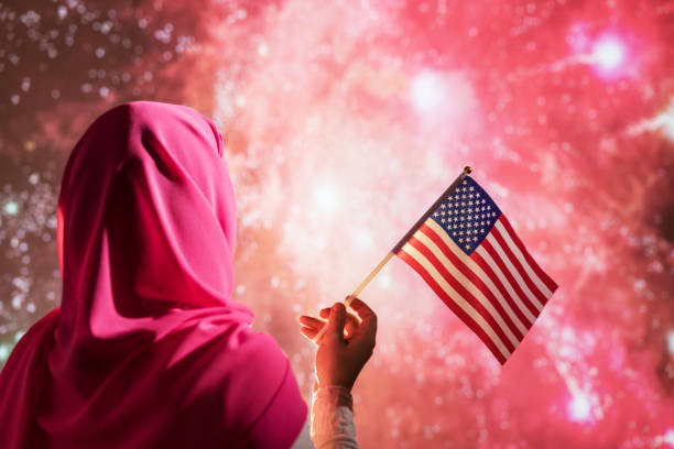 mulher muçulmana em um cachecol segurando bandeira americana durante fogos de artifício à noite. - eastern european flash - fotografias e filmes do acervo