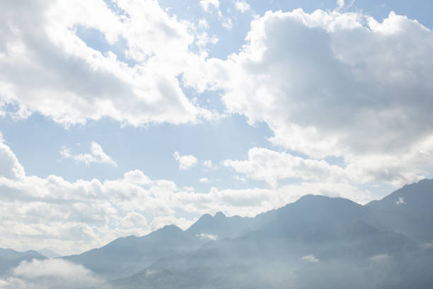 landscape view of mountain range under mist with bright sky cloud