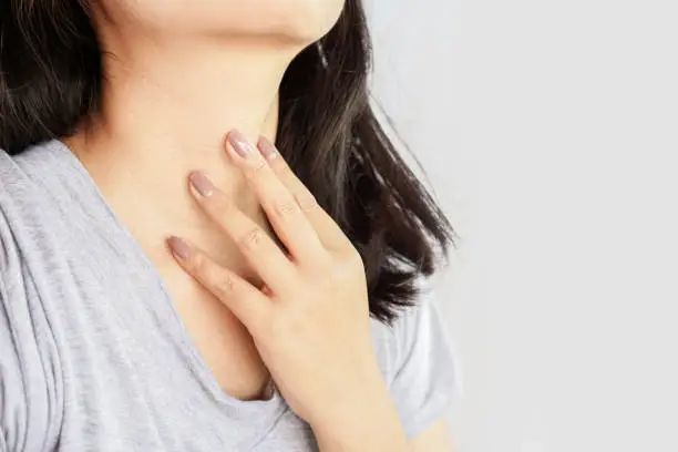 Photo of woman hand self checking thyroid gland on her neck