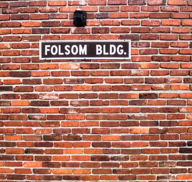 Brick Wall Red Folsom BLGD Folson BLDG Red Brick Wall with Black and White Sign. Red Brick Wall on a Commercial Building with a Sign that Reads Folson Building. old folsom stock pictures, royalty-free photos & images