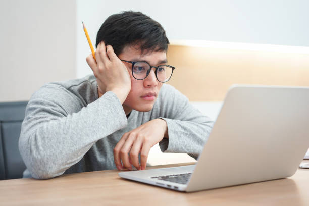 cerrar joven estudiante asiático hombre sintiéndose aburrido después de ver e-learning en el concepto de sitio web de la universidad - sleeping high school desk education fotografías e imágenes de stock