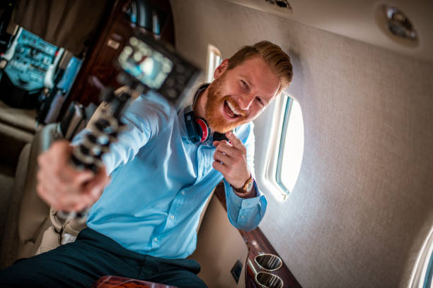 joven rico pelirrojo hombre haciendo un video blog mientras viaja en un avión privado - status symbol audio fotografías e imágenes de stock