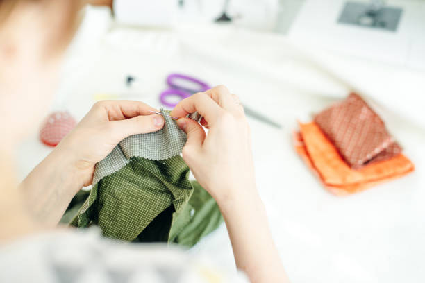 istock sewer sews up the hole in the pants in studio 1200905972