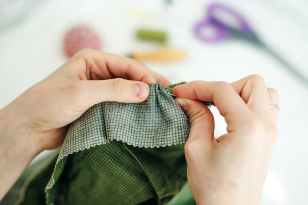 istock sewer sews up the hole in the pants in studio 1200905984