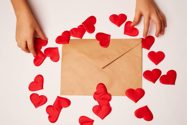 istock Kraft the envelope with red hearts on a white background.Congratulations on Valentine's Day. Hands, top view 1200909719