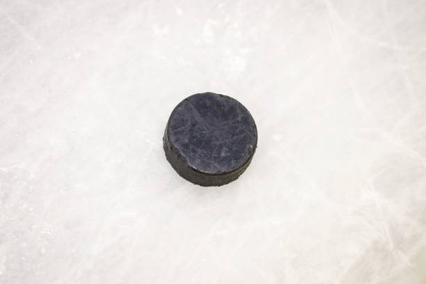 istock Black ice hockey rubber puck located on ice rink. 1200912085