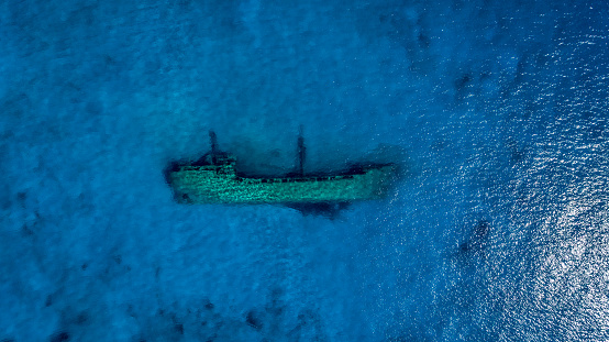 Shipwreck lying on the bottom of shallow sea water on south Peloponnese. View from above made with drone.
