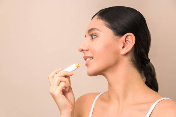 istock lips care and protection. woman applying balm on lips 1200912483