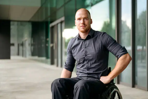 Photo of Outdoor portrait of young businessman in wheelchair