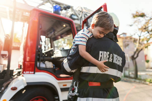 firefighter carrying stressed little boy - rescue worker imagens e fotografias de stock