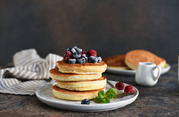 istock Beautiful pancakes with berries and sauce on a dark concrete background. 1200916769