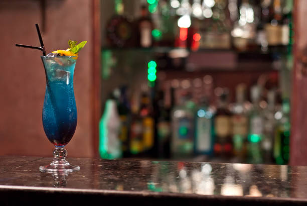 istock Blue cocktail on the bar counter. Drink with martini, gin, rum, tequila and fruit on the background of bottles with alcohol. Glass with booze on a marble board. 1200917616