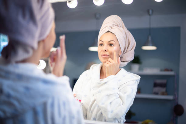 istock Young woman applying face cream. 1200918426