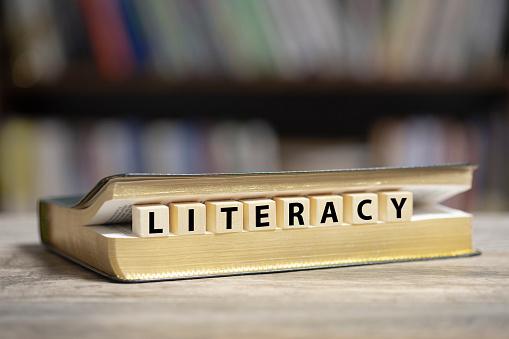 Book on desk with Literacy word written on wooden cubes