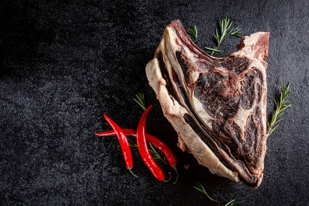modern kitchen. dry aged beef, veal meat with red pepper and rosemary lies on a black background. board background image, copy space text, top view - scotch steak imagens e fotografias de stock