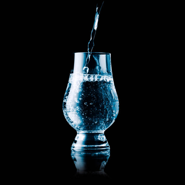 istock Liquid poured into a glass - blue toned isolated on black 1200925449