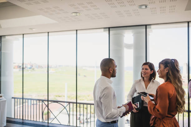 istock Young colleagues discussing by window at corporate event 1200928621