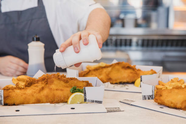 Shaking salt on boxes of fresh fish and chips