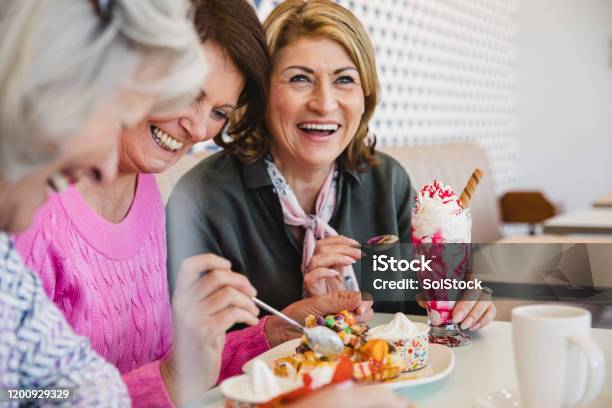 Cheerful Senior Women Laughing Together In Ice Cream Parlour Stock Photo - Download Image Now