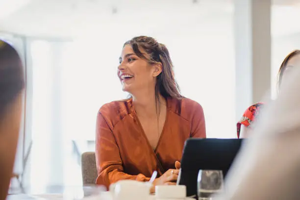 Confident young woman laughing during work meeting, success, relaxed, enjoyment
