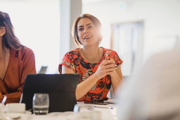 confident young businesswoman listening carefully at conference table - candid imagens e fotografias de stock