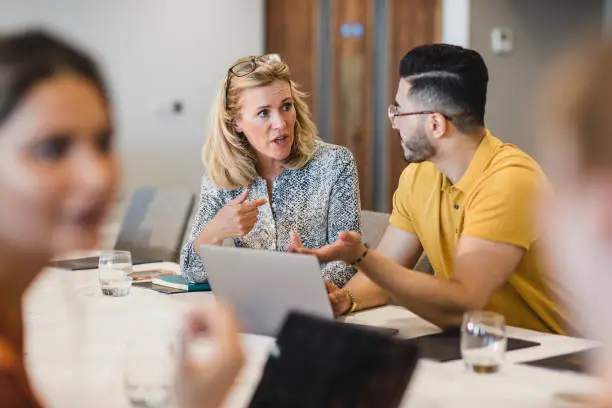 Confident woman explaining to coworker during business meeting, leadership, manager, role model