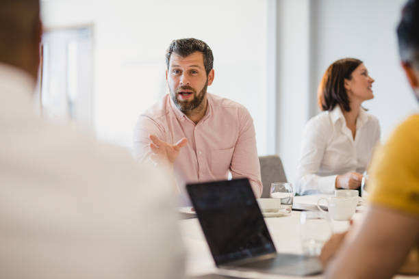 istock Mature man with beard talking to colleagues at conference table 1200929463