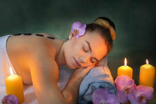 young woman relaxing during hot stone massage in luxury spa - lastone therapy imagens e fotografias de stock