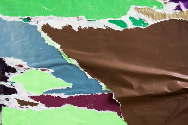 istock Brown, green and grey torn and crumpled paper placards on billboard with old peeling posters texture background. 1200931357
