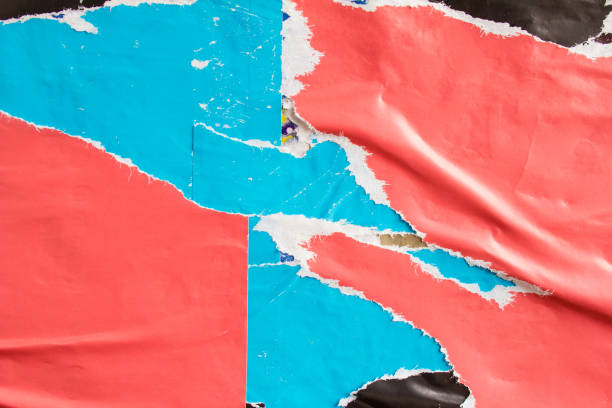istock Red and blue torn and crumpled paper placards on billboard with old peeling posters texture background. 1200931704