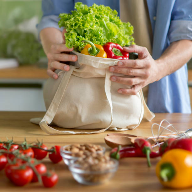 istock Man holding big cotton reusable bag full of vegetables 1200931982