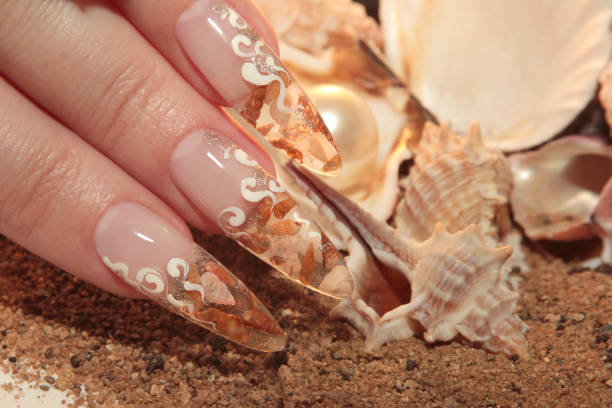 Aquarium nautical nail art design on long nails transparent with small shells inside and sequins on the outside.Creative manicure on long nails.