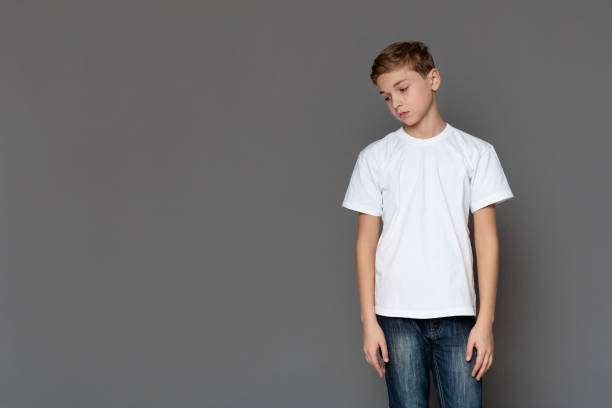 istock Sad teen boy standing alone, grey studio background 1200932188