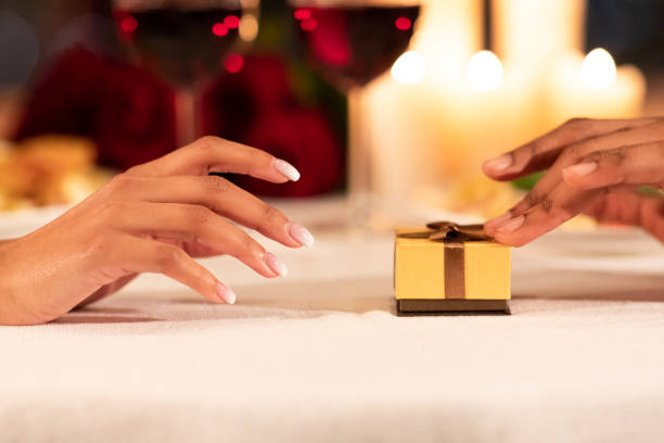 istock Male Hands Pushing Gift Box To Girlfriend On Restaurant Table 1200932357