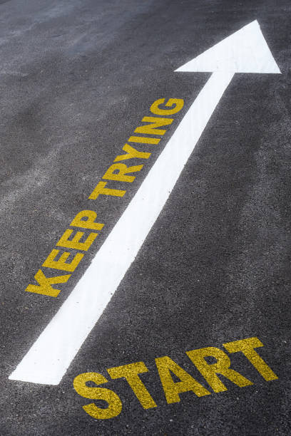 istock Start and keep trying words with arrow sign marking on road surface 1200932548