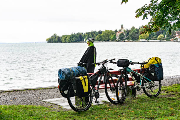 istock Woman cyclist standing next to bicycles looking at lake. 1200934171
