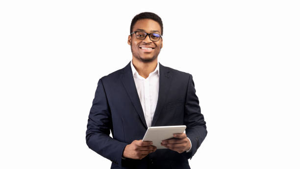 Smiling black guy standing with tablet at studio Online Education. Smiling afro man holding digital tablet and looking at camera over white studio background, copyspace salesman stock pictures, royalty-free photos & images