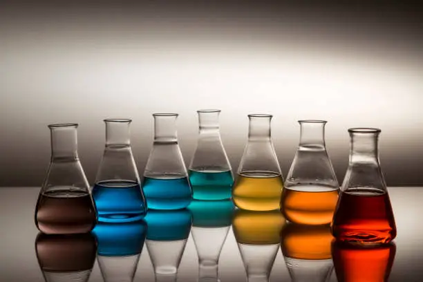 Scientific laboratory glass erlenmeyer flask filled with colorful liquid forming rainbow.