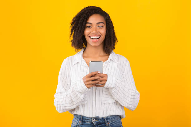 istock Smiling afro girl using cell phone looking at camera 1200937066