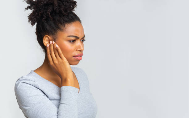 中耳炎に苦しむアフロの女の子は、彼女の炎症を起こした耳をこすり - alternative medicine audio ストックフォトと画像