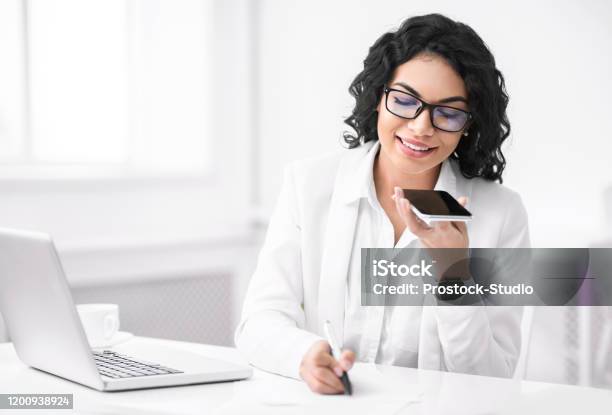 Smiling Hispanic Woman Using Voice Assistant On Phone Stock Photo - Download Image Now