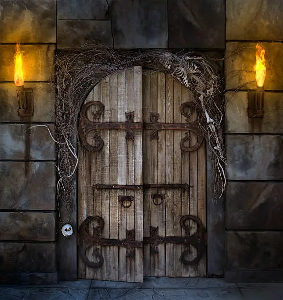 Spooky dungeon door flanked with two flaming torches and decorated with twigs and skeleton bone