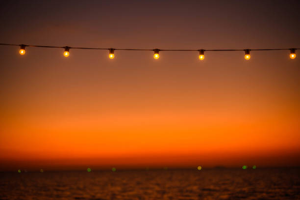 istock Sunset scene of light bulbs on string wire 1200943260