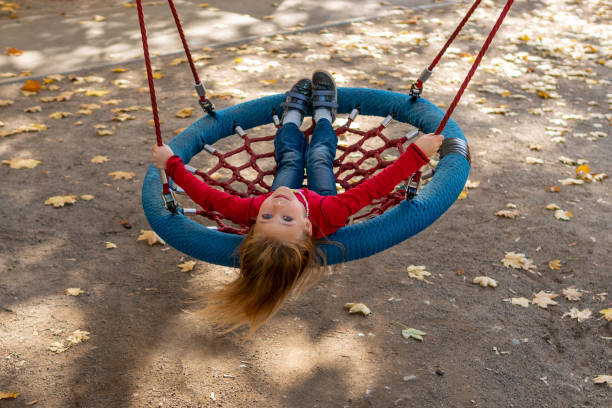 smiling little beautiful girl riding on a swing with a net